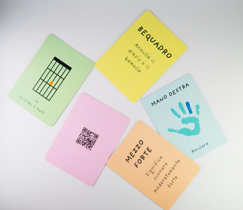 K&ouml;nnte beinhalten: Eine Sammlung farbenfroher Karteikarten mit musikalischen Begriffen und Symbolen. Die Karten sind in verschiedenen Farben gehalten, darunter Gr&uuml;n, Gelb, Rosa, Blau und Orange. Jede Karte enth&auml;lt Text und Illustrationen, wie z. B. ein Gitarrenakkorddiagramm und einen Handabdruck.