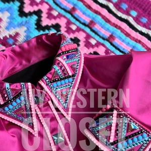 May include: A close-up of a vibrant pink western show shirt, adorned with detailed beadwork in blue, pink, and silver. The shirt has the text "WESTERN CLOSETS" overlaid. A patterned blanket in the background provides a contrasting texture.