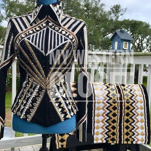 May include: Black equestrian show jacket with silver, gold, and brown detailing. The jacket has a high collar and long sleeves. A matching saddle pad with a geometric pattern in black, white, and gold is also shown.