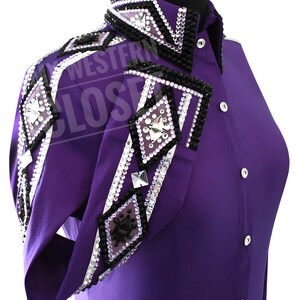 Può includere: Una camicia da spettacolo viola con abbellimenti decorativi. La camicia presenta un colletto e polsini con dettagli neri e argento, tra cui strass e motivi geometrici. Anche le maniche sono decorate con disegni simili.