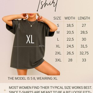 May include: Dark green t-shirt with a size guide chart. The chart lists sizes S to 3XL, with width and length measurements in inches. The text on the shirt reads "XL". The model is wearing an XL.