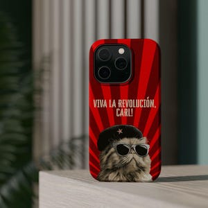 May include: A red phone case featuring a cat wearing sunglasses and a beret with a star. The case has a red radial design and the text "VIVA LA REVOLUCIÓN, CARL!"
