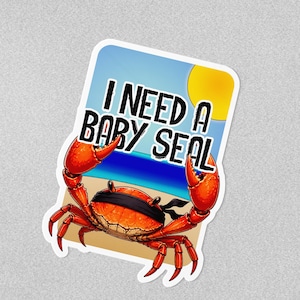 May include: A rectangular sticker featuring a bright orange crab wearing a black blindfold over its eyes. The crab is on a sandy beach with a blue ocean and a yellow sun in the background. The text I NEED A BABY SEAL is printed in black.
