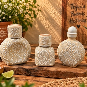 May include: Three ceramic bottles with a tan base and white hand-painted fan-shaped patterns. Two bottles are round with matching tan lids, and one is square with a tan lid. The bottles feature intricate, repeating floral-like designs.