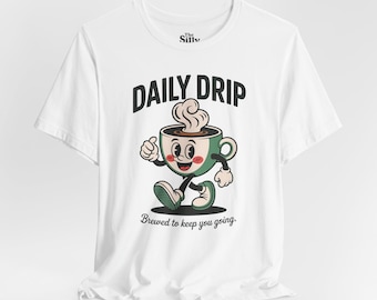May include: White t-shirt with a cartoon coffee cup character. The cup has a smiling face, arms, and legs. The text "DAILY DRIP" is above the cup, and "Brewed to keep you going" is below the cup.