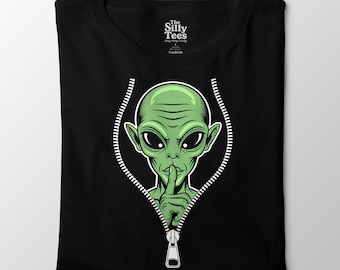 May include: Black t-shirt featuring a green alien graphic with a finger over its lips, as if shushing. The alien is inside a white zipper design. The text "The Silly Tees" is at the top.