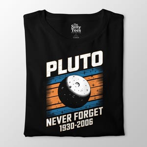 May include: Black t-shirt with a graphic of Pluto and the text "PLUTO NEVER FORGET 1930-2006". The graphic features a detailed illustration of Pluto with a blue and orange striped background.