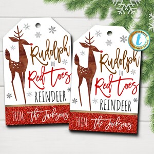 Könnte beinhalten: Zwei druckbare Geschenkanhänger mit einem Comic-Rentier mit dem Text "Rudolph the Red Toes Reindeer" und "From: The Jacksons". Die Anhänger sind weiß mit einem roten Glitzerhintergrund und silbernen Schneeflocken.