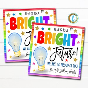 Op de afbeelding: Twee kleurrijke, printbare cadeaulabels met een gloeilampgrafiek en de tekst "Hier is voor een stralende toekomst! We zijn zo trots op je! Liefs, de familie Jackson."