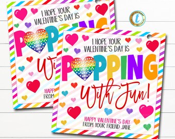 Puede incluir: Dos tarjetas de San Valentín con un juguete pop-it en forma de corazón arcoíris. Las tarjetas tienen un borde a rayas de colores y el texto "¡Espero que tu día de San Valentín sea divertido!" y "Feliz día de San Valentín de tu amiga Jane".
