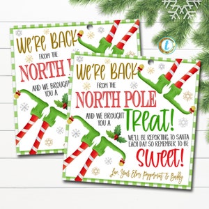 May include: Two Christmas gift tags featuring green elves with red and white striped legs. The tags have a green and white checkered background with snowflakes. The text on the tags reads "We're back from the North Pole and we brought you a Treat! We'll be reporting to Santa each day so remember to be Sweet! Love, Your Elves Peppermint & Buddy."