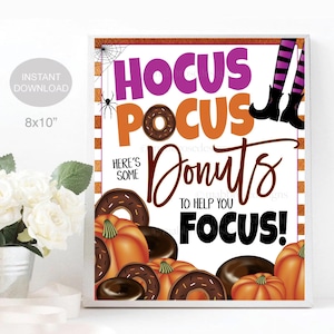 May include: A printable 8x10 inch sign with a Halloween theme. The sign features a purple and orange background with the text "Hocus Pocus Donuts to help you Focus!"  The sign is decorated with donuts, pumpkins, and witches' legs.