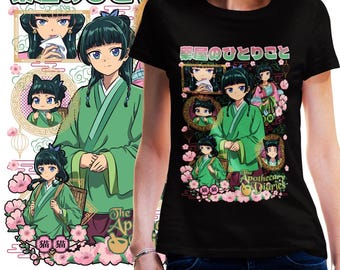 Puede incluir: Camiseta negra con una vibrante ilustración de estilo anime. El diseño presenta un personaje central con una túnica verde, enmarcado por retratos más pequeños, flores rosas y texto japonés. También está presente el texto "The Apothecary Diaries".