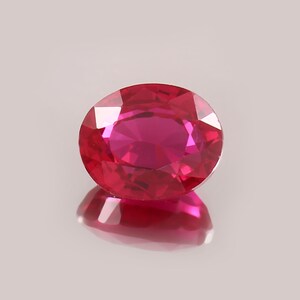 Peut inclure: Un rubis taillé en rond, avec de multiples facettes. La gemme est d'un rouge profond, reflétant la lumière. Le rubis repose sur une surface réfléchissante, créant un effet miroir. Le rubis mesure environ 1,5 cm de diamètre. Symbole de luxe et de beauté.