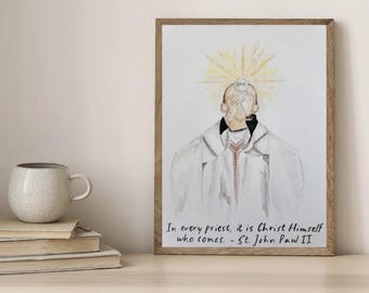 Op de afbeelding: Aquarel kunstafdruk in een houten lijst. Het kunstwerk toont een priester die een communie-hostie vasthoudt, met een stralende halo. De afdruk bevat de quote: "In elke priester is het Christus Zelf die komt. - St. John Paw II."