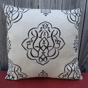 May include: A beige throw pillow with a black and white geometric pattern. The pattern is a repeating design of stylized flowers and leaves.