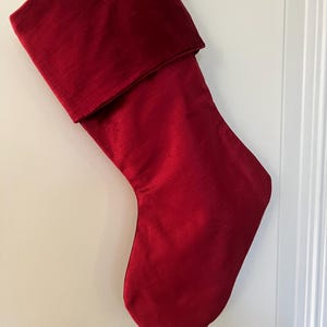 May include: A red velvet Christmas stocking with a folded cuff.