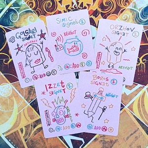 Puede incluir: Cinco cartas rosas con ilustraciones y texto dibujados a mano. Cada carta presenta un diseño diferente, incluyendo una calavera, una pecera y una espada. Las cartas están etiquetadas con términos como "Golgari Signet" y "Artifact".