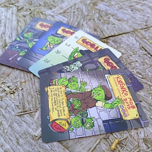 May include: A collection of game cards with goblin illustrations. The cards display various goblin characters and text such as "Krenko, Mob Boss" and "Goblin Token Creature". The cards are arranged on a wooden surface.