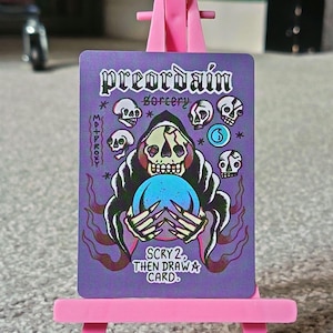May include: A purple card featuring the words "preordain sorcery" and "SCRY 2, THEN DRAW A CARD." The card depicts a Grim Reaper-like figure with a skull face holding a blue orb, surrounded by skull illustrations.