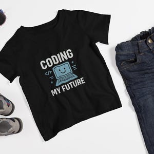 May include: Black t-shirt with the text "CODING MY FUTURE" and a smiling computer graphic. The shirt is paired with blue denim jeans, sunglasses, and gray and blue sandals. A fun outfit for a young coder.