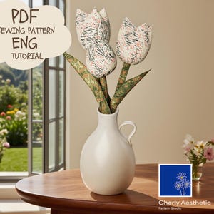 May include: A white ceramic vase holds three fabric tulips with patterned petals and green leaves. The tulips are in a white vase on a wooden table. The image includes text that says "PDF Sewing Pattern ENG Tutorial".