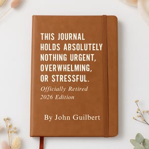 May include: A brown journal with the text "THIS JOURNAL HOLDS ABSOLUTELY NOTHING URGENT, OVERWHELMING, OR STRESSFUL." The journal also includes the text "Officially Retired 2026 Edition" and "By John Guilbert."