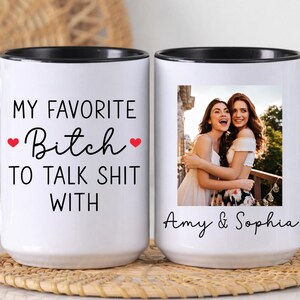 May include: White ceramic mug with a black handle and rim. The mug features the text "MY FAVORITE Bitch TO TALK SHIT WITH" with red heart accents. The other side displays a photo of two women with the names "Amy & Sophia".