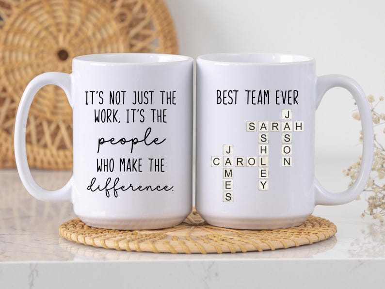 K&ouml;nnte beinhalten: Zwei wei&szlig;e Keramikbecher mit schwarzem Text. Auf einem Becher steht "IT'S NOT JUST THE WORK, IT'S THE people WHO MAKE THE difference." Der andere Becher sagt "BEST TEAM EVER" mit Namen.
