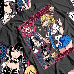 Könnte beinhalten: Schwarzes T-Shirt mit Anime-Illustrationen. Das Design zeigt ein zentrales Bild eines blonden Charakters in Schuluniform mit dem Namen "MARIN KITAGAWA" in Rosa. Zusätzliche Anime-Charaktere sind in kleineren Kästchen abgebildet.