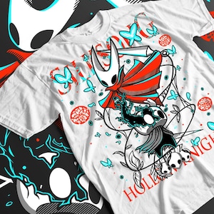 Puede incluir: Camiseta blanca con un diseño gráfico en rojo y turquesa. El diseño presenta un personaje con capa, mariposas y el texto "Hollow Knight".