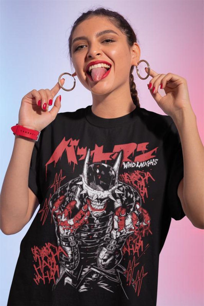 May include: Black t-shirt featuring a graphic of a skeletal figure with a horned helmet and the text "WHO LAUGHS" in white. Red Japanese text is above the graphic. The figure is surrounded by the word "HAHA" in red.