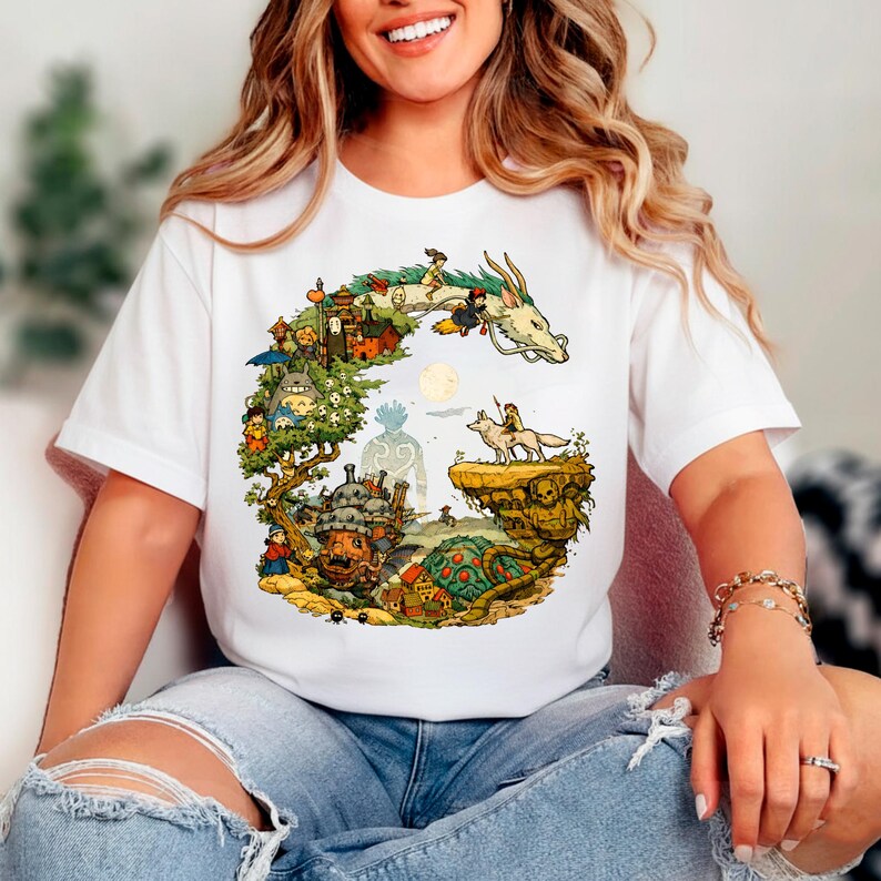 Puede incluir: Camiseta blanca con una colorida ilustraci&oacute;n de un drag&oacute;n, personajes y un paisaje fant&aacute;stico. El dise&ntilde;o incluye un drag&oacute;n, un lobo y otras figuras. La obra de arte es detallada y vibrante, con un tema caprichoso.