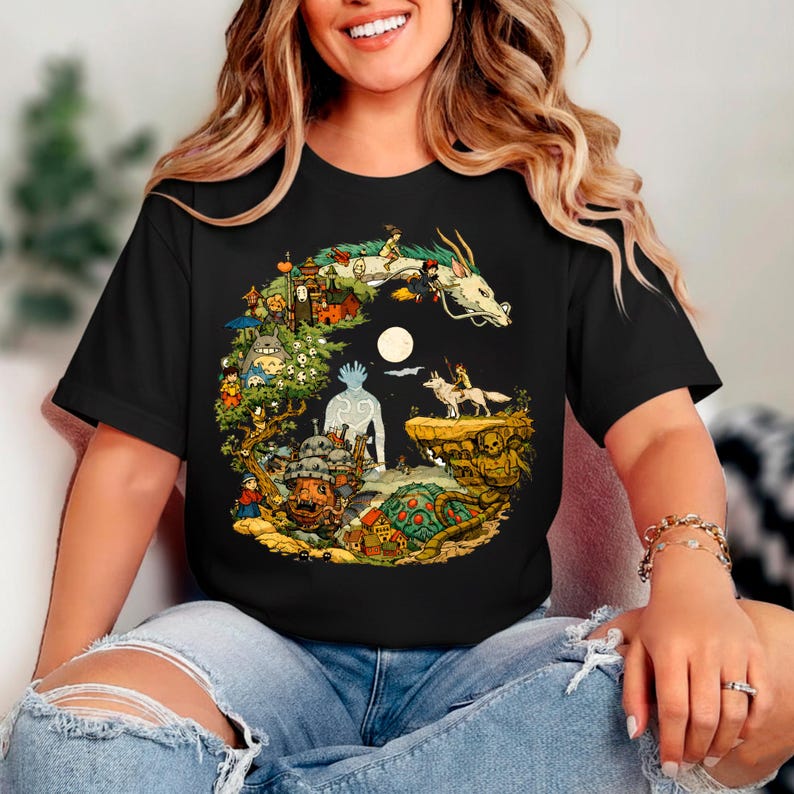 Puede incluir: Camiseta negra con un dise&ntilde;o gr&aacute;fico colorido que representa escenas y personajes de una pel&iacute;cula de animaci&oacute;n fant&aacute;stica. El dise&ntilde;o incluye un drag&oacute;n blanco, una luna llena y varias otras criaturas y edificios. La camiseta tiene mangas cortas y cuello redondo.