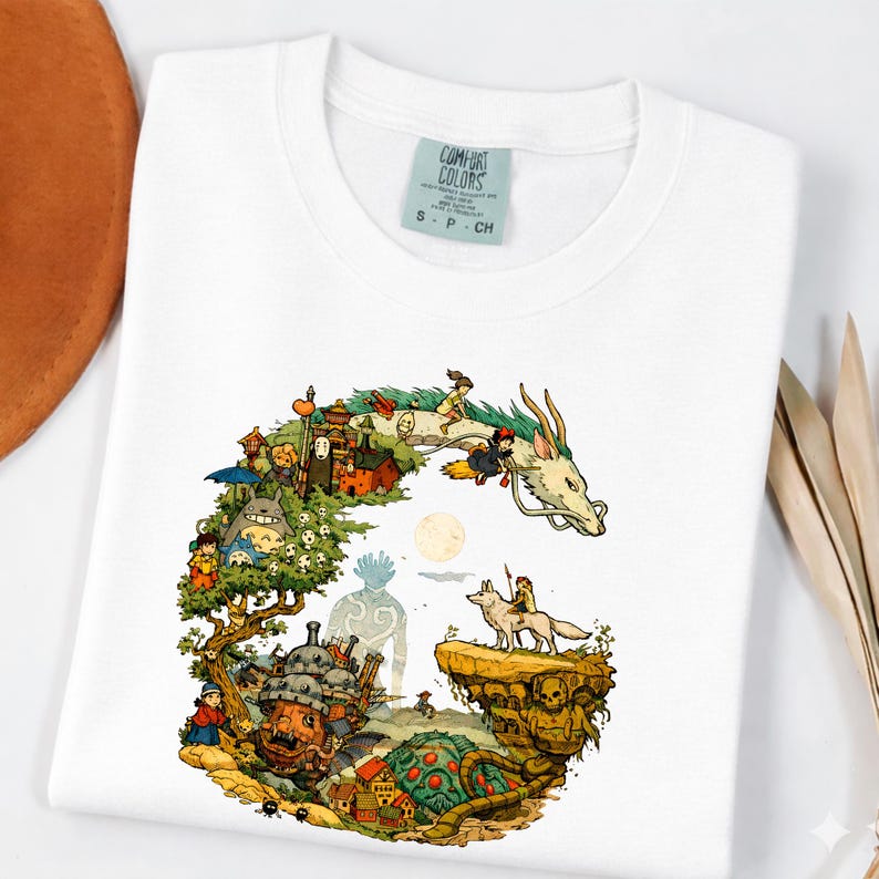Puede incluir: Camiseta blanca Comfort Colors con una colorida ilustraci&oacute;n de personajes y escenas de una popular pel&iacute;cula de animaci&oacute;n. El dise&ntilde;o incluye un drag&oacute;n, un bosque y varias figuras. La camiseta tiene cuello redondo y mangas cortas.