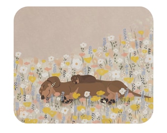 Puede incluir: Un posavasos cuadrado con una ilustración de dos perros salchicha descansando en un campo de flores. El perro más grande es marrón con patas negras, y el más pequeño está encima. Las flores son blancas, amarillas y azules.