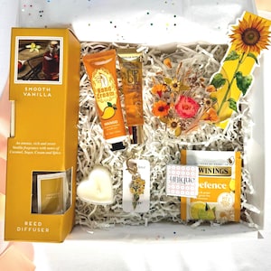 May include: A white ceramic mug with a black handle and the text "But First, Coffee" in a black, handwritten-style font. The mug is on a white surface.