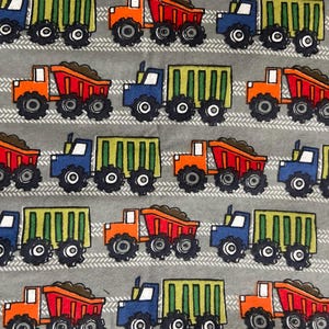May include: A repeating pattern of colorful cartoon dump trucks on a gray background. The trucks are in various colors, including orange, blue, and green, with black wheels. The trucks are filled with brown material.