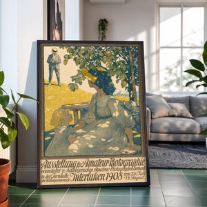 May include: A framed vintage poster titled Ausstellung für Amateur-Photographie Interlaken 1908. The illustration depicts a person in a yellow hat and a child sitting under a tree, with a person standing in the distance on a yellow grassy hill.