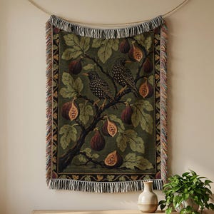 May include: A rectangular woven wall tapestry featuring a dark green background with two speckled birds perched on a fig tree branch. The design includes multiple whole and halved purple figs and large green leaves, finished with a fringed edge.