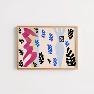 May include: A rectangular wall art print in a light wood frame featuring a cream background with abstract shapes. The design includes a large magenta zigzag, a light blue human silhouette, and various small black and blue organic leaf-like cutouts.