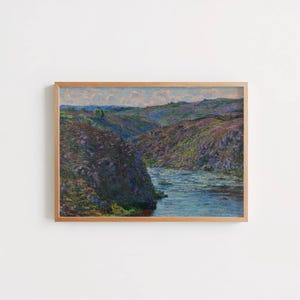 May include: A framed landscape painting depicting a river flowing through a canyon. The artwork features a palette of blues, greens, and purples, with a wooden frame. The style is reminiscent of impressionism.