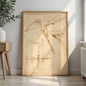 Puede incluir: Una lámina enmarcada que presenta un dibujo técnico en tono sepia de una ballesta y componentes mecánicos. La obra muestra intrincadas líneas de tinta marrón sobre un fondo color pergamino, exhibiendo bocetos de ingeniería y notas manuscritas.