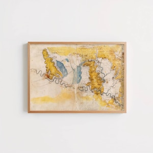 May include: A framed historical map print featuring yellow-toned landmasses, blue water bodies, and winding river systems depicted with intricate ink lines and handwritten annotations on a parchment-style background within a light wood frame.
