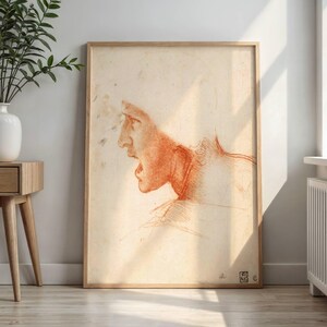 May include: A framed sketch of a human profile in a distressed style. The artwork features a red-orange drawing on a cream-colored background, with the subject's mouth open. The frame is made of light-colored wood.
