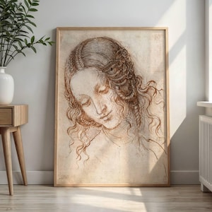 May include: A framed sepia-toned sketch of a woman with flowing hair, her head bowed. The artwork, in a wooden frame, is a detailed line drawing with shading, creating a vintage aesthetic. The image is displayed indoors, leaning against a wall.