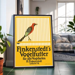 May include: A rectangular poster in a dark frame featuring a yellow background with a bird inside a cage. The text reads: Finkenstedt's Vogelfutter für alle Vogelarten H. Finkenstedt Lehrte/H. The bird has a red head, black wings, and a green tail.