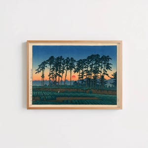 May include: Framed art print of a Japanese landscape. The artwork depicts a sunset with a red sun, silhouetted trees, and a field. The sky transitions from blue to orange. The print is in a wooden frame.