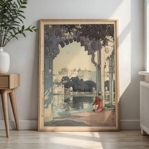 May include: A framed art print depicting a Japanese-style woodblock illustration of a stone archway overlooking a lake and a distant palace. Two figures in red and pink clothing sit by the water under the arch, with Japanese text on the left side.