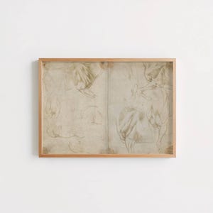 May include: A rectangular wooden frame containing a beige paper print with multiple faint, hand-drawn sketches of animal limbs and anatomical forms in dark brown ink, featuring a central vertical crease line across the aged, textured paper surface.